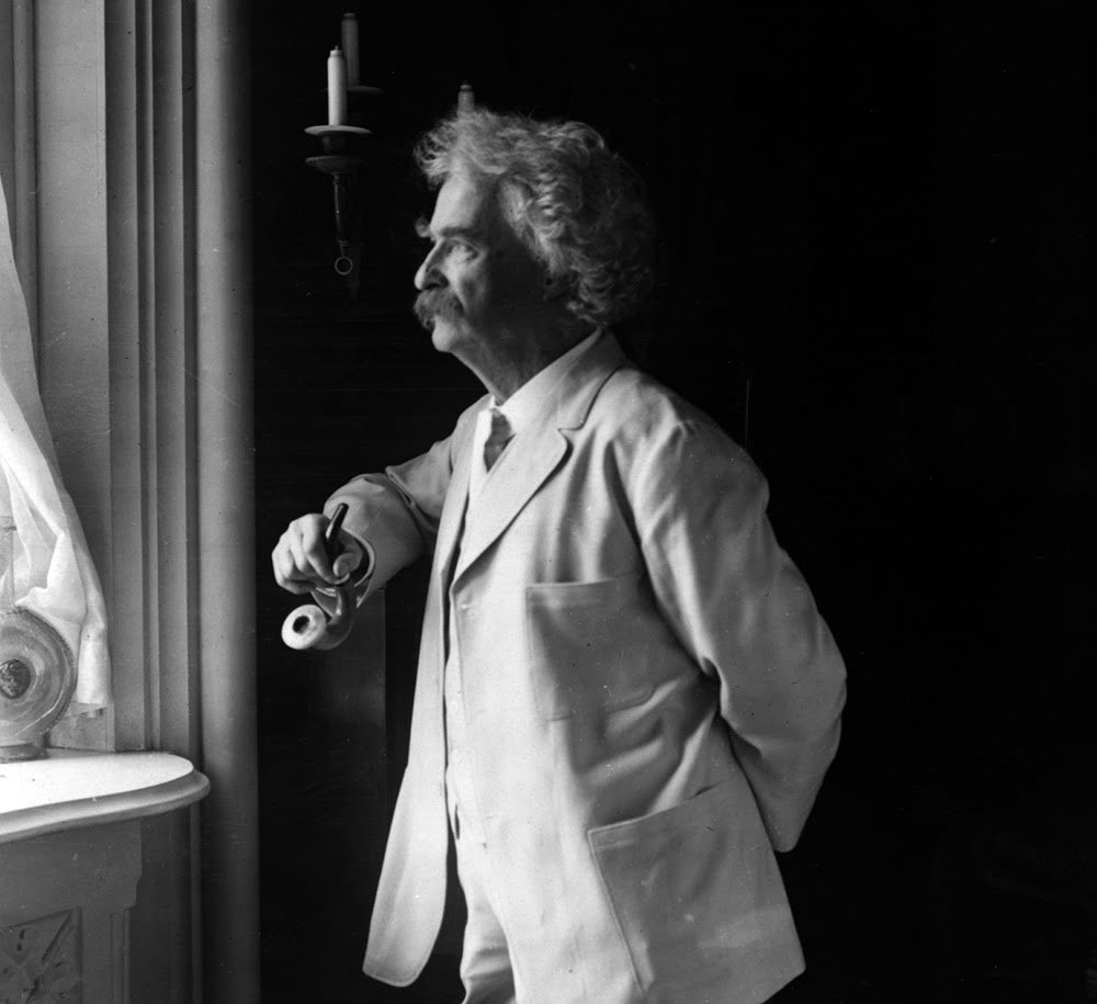 Samuel Clemens ("Mark Twain") holding a pipe and looking out the window